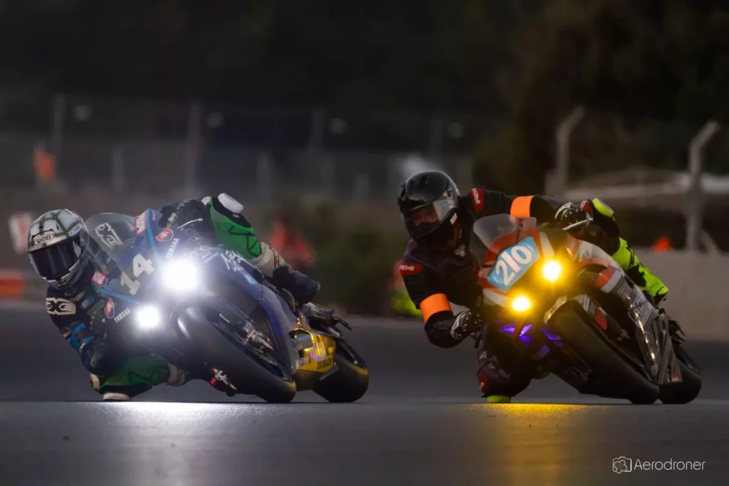 Deux motos côte à côte dans un virage de nuit